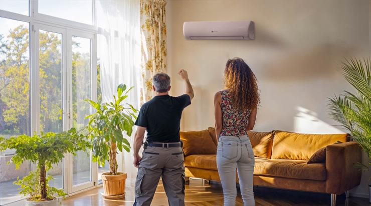 Technicien devant une clim avec un client