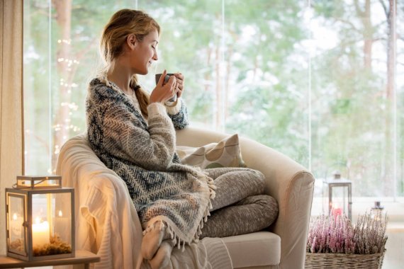 Femme buvant boisson chaude dans canapé sous un plaid