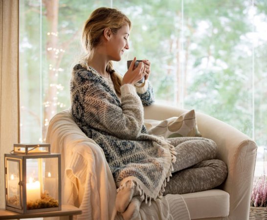 Femme buvant boisson chaude dans canapé sous un plaid