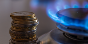 Plaque de cuisson gaz naturel en marche et pièces de monnaie posées à côté
