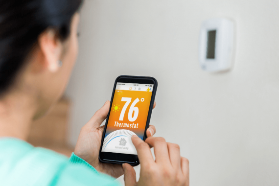 personne mettant en route son thermostat avec son smartphone