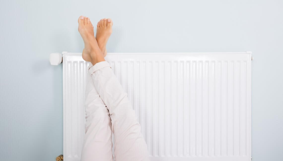 femme réchauffe ses pieds sur un radiateur