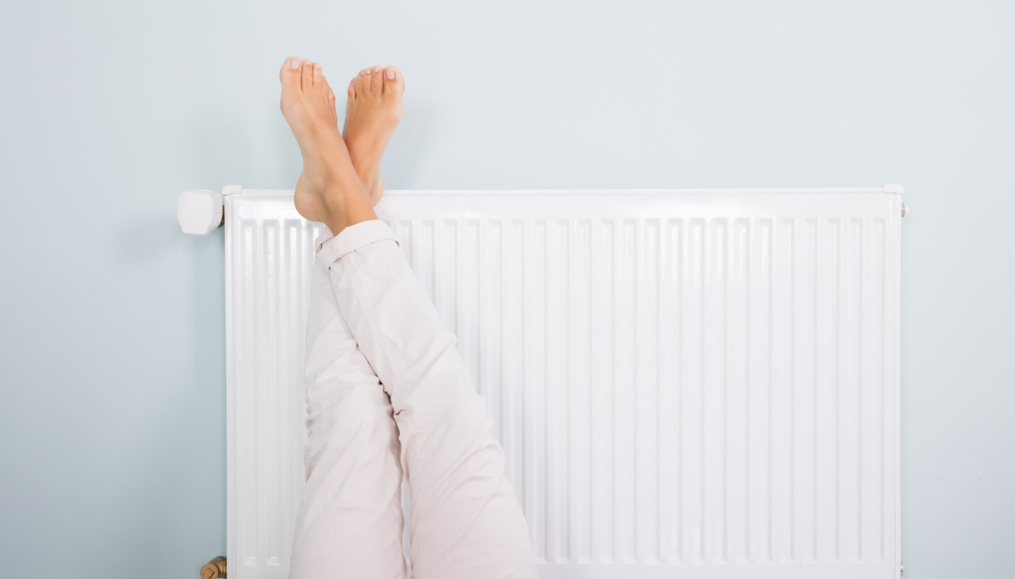 Femme se réchauffant les pieds sur le radiateur